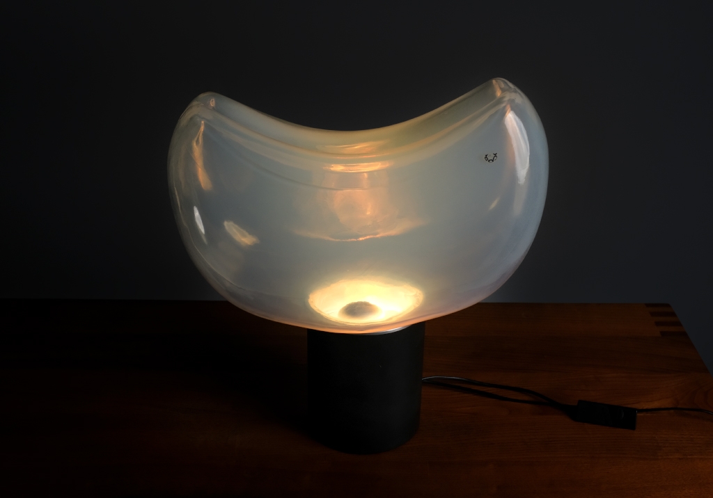 Aghia lamp by Roberto Pamio: Top front view of the lit lamp, we see the light bulb and the reflections of light on the Murano glass