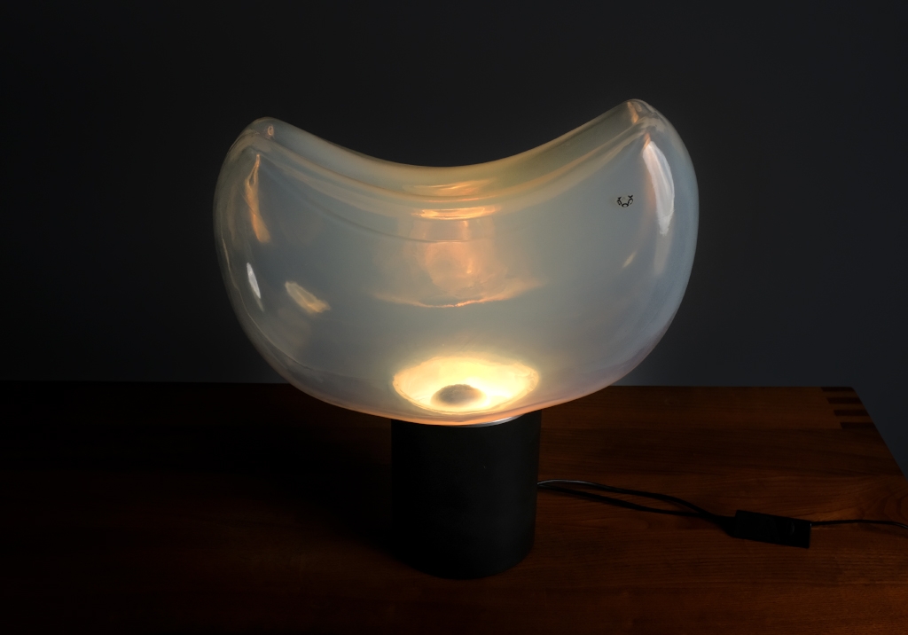Lampe Aghia de Roberto Pamio : Vue de dessus de face de la lampe allumée, on voit l'ampoule et les reflets de la lumière sur le verre de Murano