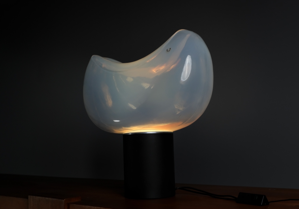 Lampe Aghia de Roberto Pamio : Vue latérale inférieure de la lampe allumée, on voit l'ampoule et les reflets de la lumière sur le verre de Murano