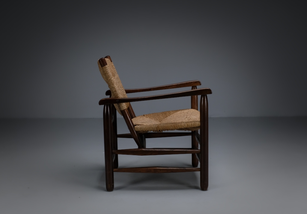 Fauteuil paillé Charlotte Perriand : vue de côté, met en évidence la stylisation de la forme traditionnelle d'une chaise de campagne
